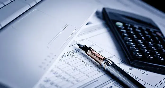 Home-office çalışma masasında dizüstü bilgisayar, hesap makinesi ve mali evraklar