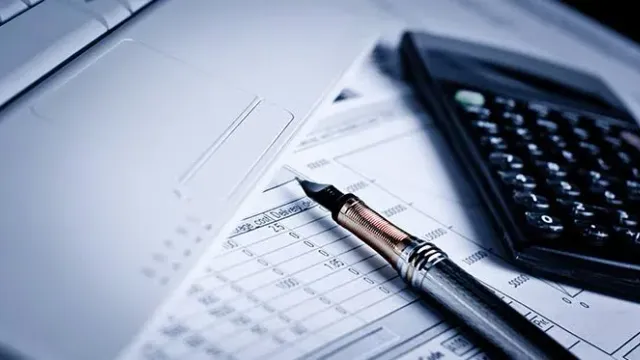 Home-office çalışma masasında dizüstü bilgisayar, hesap makinesi ve mali evraklar