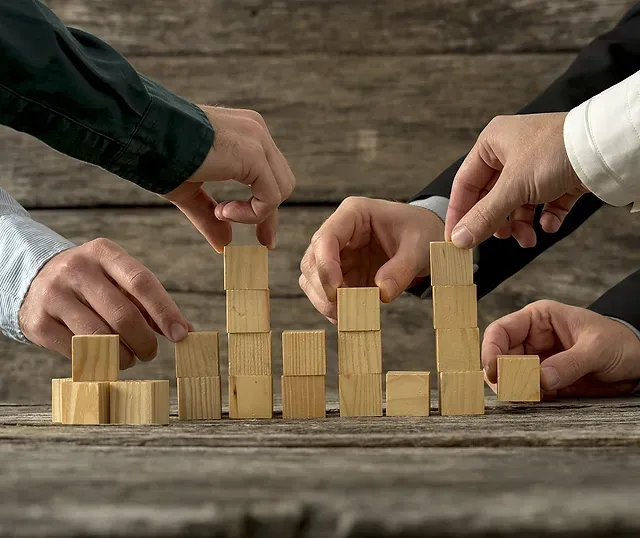 Business partners stacking wooden blocks together, symbolizing steady step-by-step growth