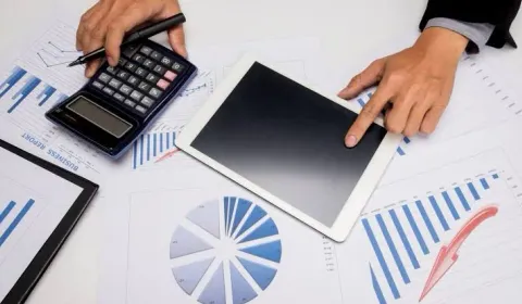 Detailed accounting work with a calculator, tablet and documents for social security processing