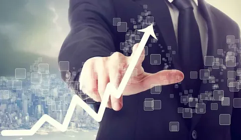A businessperson pointing at a rising chart on digital displays