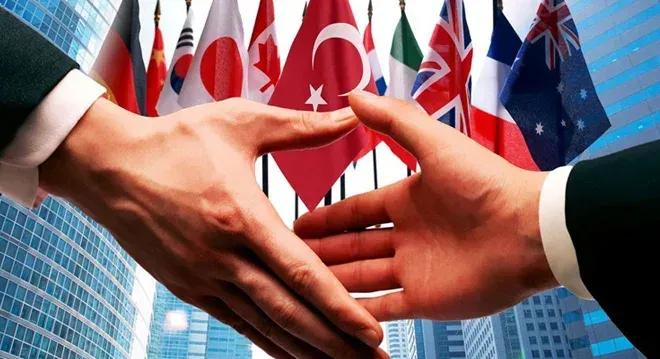Farklı ülke bayrakları önünde el sıkışan iki iş insanını gösteren, uluslararası yatırım işbirliğini simgeleyen görsel