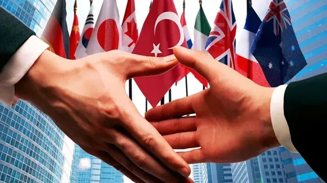 Farklı ülke bayrakları önünde el sıkışan iki iş insanını gösteren, uluslararası yatırım işbirliğini simgeleyen görsel